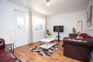 a living room with a leather couch and a tv at Prime House - St James Park - Newcastle in Newcastle upon Tyne