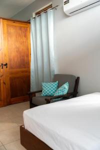a bedroom with a bed and a chair and a door at Hidden Secret in Gros Islet