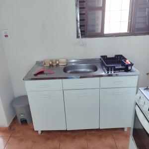 a white kitchen with a sink and a stove at Apartamento com Ar Condicionado in Nova Andradina +4 photos