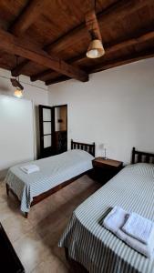 two beds in a room with wooden ceilings at Casona de coria in Ciudad Lujan de Cuyo +25 photos
