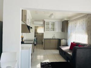 a living room with a couch and a kitchen at Kwa Mmaloapi Guest House in Rustenburg