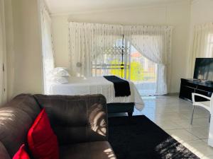 a living room with a bed and a couch at Kwa Mmaloapi Guest House in Rustenburg