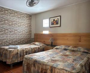 a bedroom with two beds and a brick wall at Hotel Alicia in El Puente