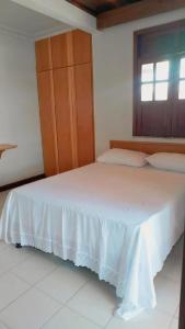 a bedroom with a white bed with a wooden cabinet at Hotel raizes in Conceição do Coité