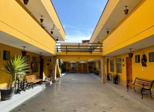 an empty courtyard of a yellow building with benches at Hotel Alicia in El Puente