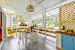 a kitchen with a table and chairs and windows at La Magia Bungalows in Puerto Viejo