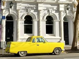a yellow truck parked in front of a hotel at Empire Apartments in Dunedin