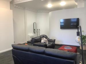 a living room with a couch and a flat screen tv at Empire Apartments in Dunedin