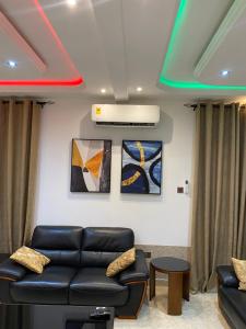 a living room with a couch and paintings on the wall at Trio Grove in Tema