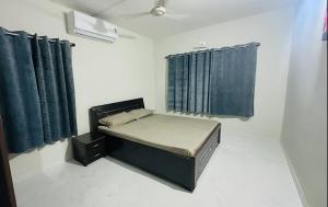a small room with a bed and blue curtains at AC Luxury Appt 2BHK in Satellite Ahmedabad in Ahmedabad