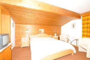 a bedroom with a white bed and a tv at Frühstückspension & Appartements Eugenie in Kitzbühel