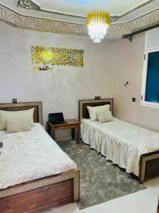 a bedroom with two beds and a chandelier at Skb Sea House Taghazout in Taghazout
