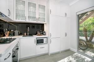 a white kitchen with white cabinets and a window at Balmoral beauty - Elevated living on the esplanade BALO1 in Sydney