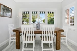 a dining room with a wooden table and white chairs at Balmoral beauty - Elevated living on the esplanade BALO1 in Sydney +5 photos