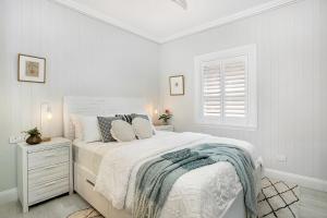 a white bedroom with a bed and a window at Balmoral beauty - Elevated living on the esplanade BALO1 in Sydney