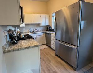 a kitchen with a stainless steel refrigerator and white cabinets at Downtown Coastal Trail 2 BDR 1 BTH Sleeps 2-6 in Anchorage