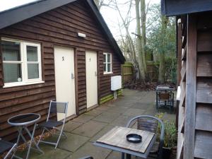 a patio with chairs and a table in front of a house at Woodland Lodge in Hoddesdon