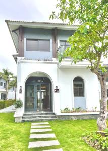 a white house with a green yard at Cozy Villa V3G08A in Sonasea - Vân Đồn - Gần biển- Đầy đủ tiện nghi in Thâm Câu