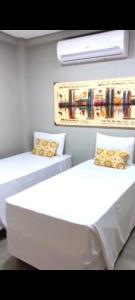 a room with two white beds with pillows at Aconchego in Paradise Cancun in Águas de Lindóia