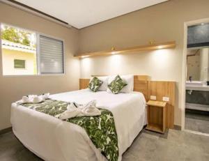 a bedroom with a large white bed and a window at Aconchego in Paradise Cancun in Águas de Lindóia