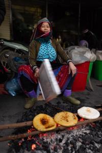 a woman is cooking food on a grill at Mountain Sprout Homestay in Dồng Văn
