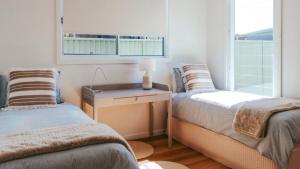 two beds in a room with a desk and a window at Old Bark House in Old Bar