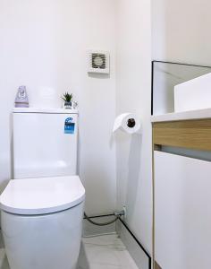 a white bathroom with a toilet and a sink at Close to New Lynn train station 3 bedroom townhouse in Auckland