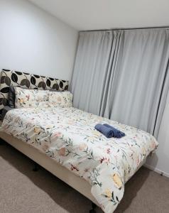 a bedroom with a bed with a flowery comforter at Close to New Lynn train station 3 bedroom townhouse in Auckland