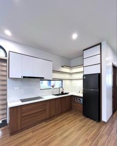 a kitchen with white cabinets and a black refrigerator at Cozy Villa V3G08A in Sonasea - Vân Đồn - Gần biển- Đầy đủ tiện nghi in Thâm Câu