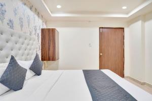 ハイデラバードにあるHotel La Sky Boutique Airport Zone Hyderabadの白いベッドと木製のドアが備わるベッドルーム1室が備わります。
