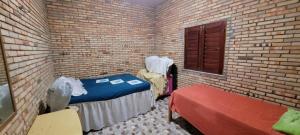 um quarto com uma cama e um banco numa parede de tijolos em Casa de praia em Paracuru
