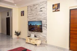 a living room with a tv on a stone wall at Executive 2 Bedroom RealShala East Legon Hills in Maijaw
