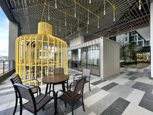 Gua SaiにあるAlinea Suites Shah Alam by Rumah Mamaのテーブルと椅子と金の檻のあるレストラン