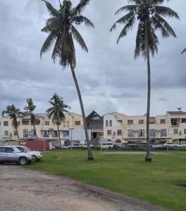 two palm trees and a car parked in a park at Grace Hotel in Honiara