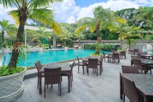 a resort with a swimming pool with tables and chairs at Novotel Solo in Solo