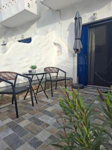 a patio with two chairs and a table and an umbrella at FERMINA KaGa kythnosuites in Mérikhas