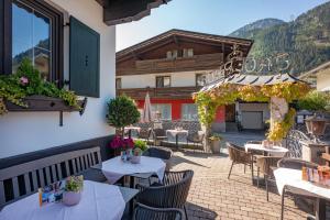 マイヤーホーフェンにあるHotel Jägerhof Mayrhofenのテーブルと椅子のあるパティオと建物