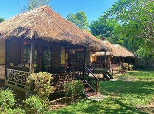 a small hut with a thatched roof and chairs at Villa De Pai in Pai