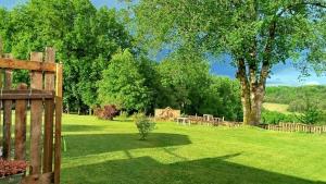 un cortile verde con una staccionata di legno e un albero di Studio indépendant au calme a Château-lʼÉvêque