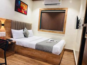 a small bedroom with a bed and a window at Hotel Airport Palace in Mumbai