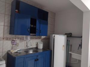 a kitchen with blue cabinets and a sink and a refrigerator at Cidreira-Salinas Casinha in Cidreira
