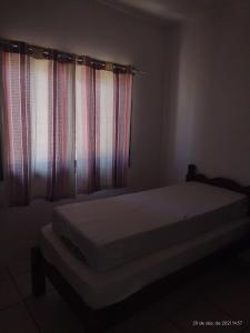 a bedroom with a bed and curtains in a room at Cidreira-Salinas Casinha in Cidreira