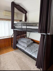 two bunk beds in a room with a window at 旅人宿ゆるっと in Iburi