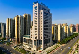 a tall white building in the middle of a city at Jinling Grand Hotel in Hefei