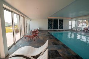 a swimming pool with chairs and a table in a house at Hôtel Le Manoir du Roselier in Plérin