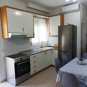 a kitchen with white cabinets and a stainless steel refrigerator at Violetta house by the sea in Skála Foúrkas