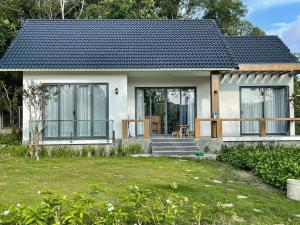 a small white house with glass doors and a yard at Baisao Villa in Phú Quốc