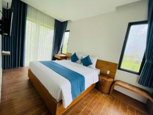 a bedroom with a large bed with blue and white sheets at Baisao Villa in Phú Quốc
