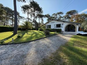Una pequeña casa blanca con entrada para coches. en Villa Dune & Océan, en Labenne