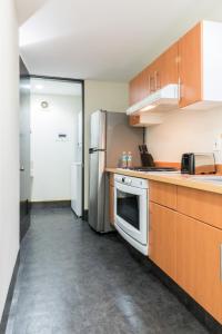 a kitchen with wooden cabinets and a stainless steel refrigerator at Boutique Apartment Puerta Alameda-801 in Mexico City
